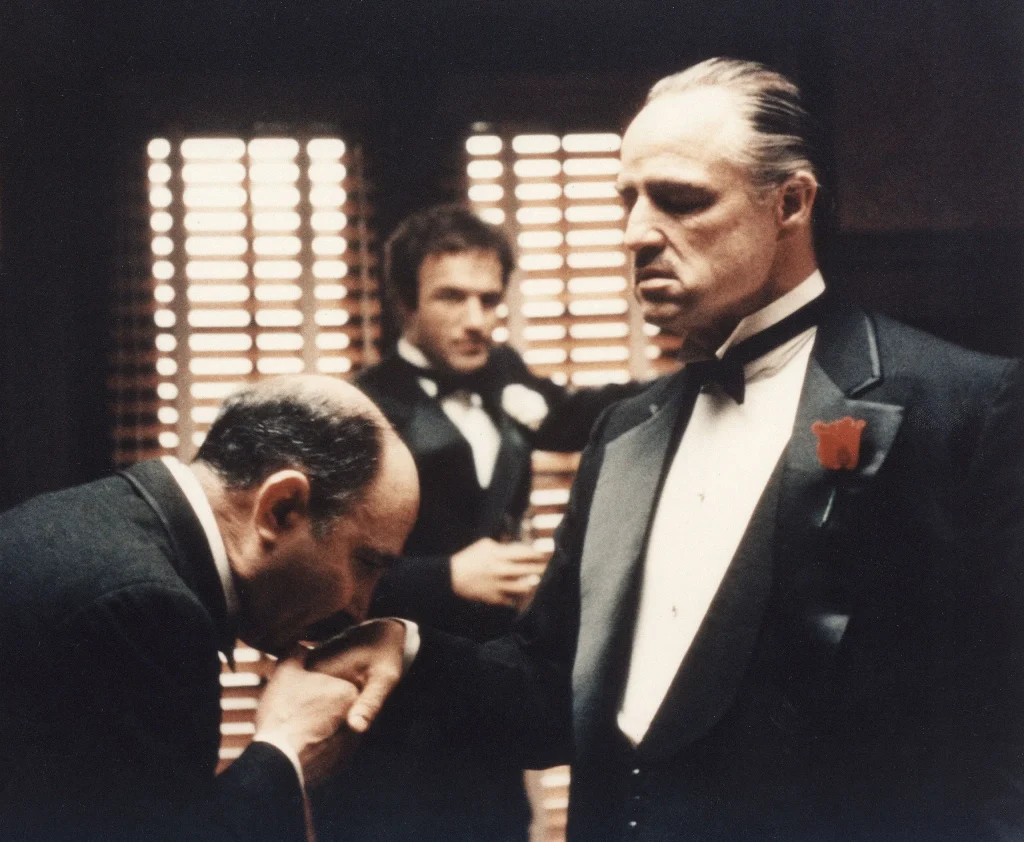 Where to Watch The Godfather scene still showing a classic dramatic moment from the film with key characters